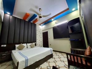 a bedroom with a bed and a flat screen tv at Karachi Guest House in Karachi