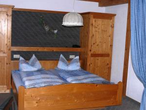 una cama de madera con almohadas azules. en Gästehaus Klingele, en Todtmoos