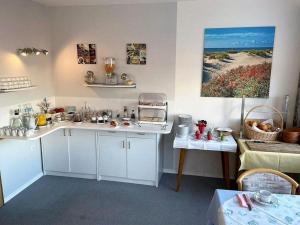 a kitchen with white cabinets and a painting on the wall at Studiozimmer-12 in Borkum