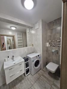 ein Badezimmer mit Waschmaschine und Waschbecken in der Unterkunft Apartament Sea & Sun Letnica in Danzig