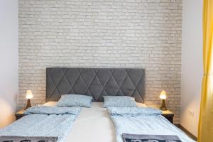 een slaapkamer met twee bedden en een bakstenen muur bij Dream Apartman Aliga II in Balatonvilágos