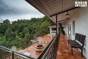 Un balcón de una casa con una mesa y sillas. en StayVista at Aspen Heights Hidden In Clouds, en Mussoorie