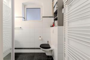 a white bathroom with a toilet and a window at 125qm Loft nahe Stadt und Hafen in Hamburg