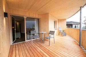 a wooden deck with chairs and a table on it at Hotel Erlebach 4-Sterne-Superior in Riezlern