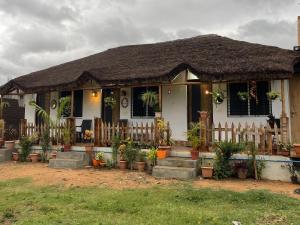 a house with a fence and potted plants in front of it at Khushi's Cottage in Hampi