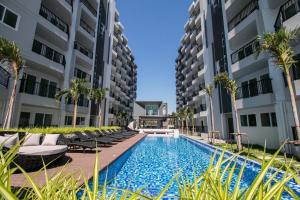 a swimming pool with chaise lounge chairs next to buildings at BEACH Condo Mae Phim in Ban Tha Fat