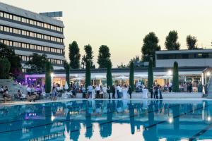 a group of people standing around a pool in front of a building at Living Place Hotel in Villanova