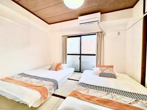 two beds in a room with a window at 江元浅草 in Tokyo