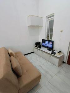 a living room with a couch and a desk with a computer at Villa Aisyahh in Sengkaling