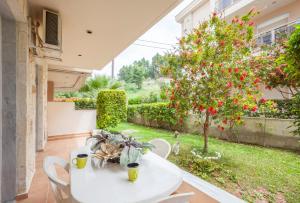 a white table and chairs and a tree with red flowers at Icon Deluxe accommodation in Pefkochori