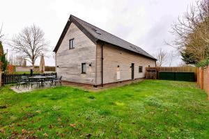 eine große Holzscheune mit einem Tisch in einem Hof in der Unterkunft Finest Retreats - Oak Cottage in Bidford