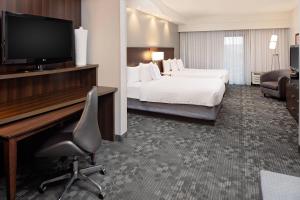 a hotel room with a bed and a desk with a television at Courtyard by Marriott Houma in Houma +27 photos