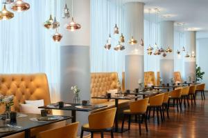 a dining room with tables and chairs and chandeliers at Avani Frankfurt City Hotel - previously NH Collection Frankfurt City in Frankfurt