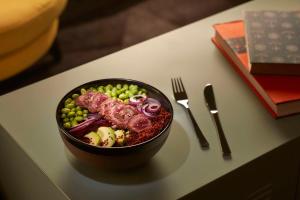 a bowl of food on a table with a fork and knife at Avani Frankfurt City Hotel - previously NH Collection Frankfurt City in Frankfurt +37 photos