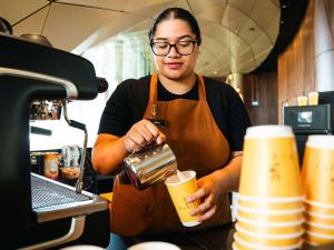 a woman in a kitchen making a drink at Pullman Auckland Airport in Auckland
