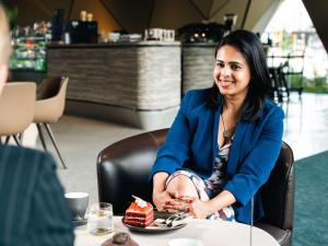 a woman sitting at a table with a piece of cake at Pullman Auckland Airport in Auckland