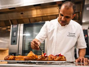 a man in a kitchen preparing food on a grill at Pullman Auckland Airport in Auckland