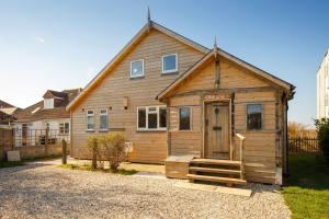 ein kleines Holzhaus mit einer Veranda auf einer Straße in der Unterkunft Bright & Dreamy On the Beach Garden & Balcony in Bracklesham Bay