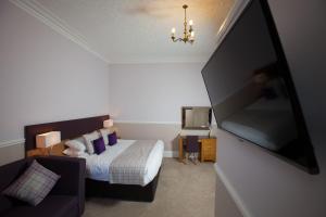 a bedroom with a bed and a flat screen tv at Cressfield Country House Hotel in Ecclefechan