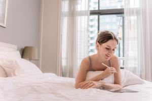 a woman sitting on a bed smoking a cigarette at Centre Point Hotel Chidlom Bangkok in Bangkok