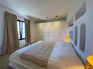 a white bedroom with a large bed and a window at Modern villa in Lajares with private pool in La Oliva +20 photos