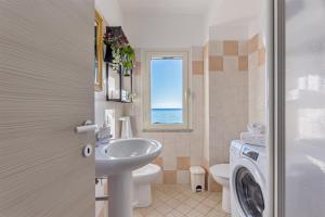 a bathroom with a sink and a toilet and a window at Casa Mulas in Tertenìa