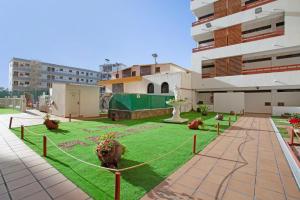 a courtyard of a building with a green lawn at El Nido de los Ángeles in Playa del Ingles