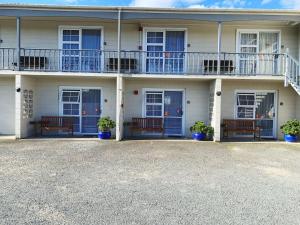 a white building with blue doors and benches at Kerry's Motel in Rotorua
