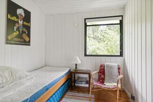 a bedroom with a bed and a window and a chair at The Red Summer House With The Lush Garden At Asnæs in Asnæs
