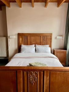 a bedroom with a wooden bed with white sheets at La Ronce Home in Écaussinnes-dʼEnghien