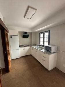 a kitchen with white cabinets and a sink and a microwave at El pasaje Apart in Ronda