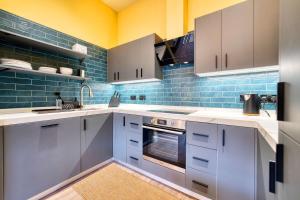 a kitchen with white cabinets and blue tiles at Spacious Central Station 2 Bed Apartment B3 in Glasgow