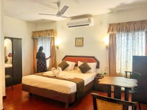 a woman standing in a bedroom with a bed at Mangotree Kochi in Cochin +11 photos