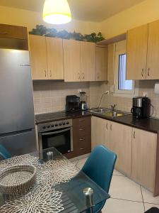 a kitchen with wooden cabinets and a table with a blue chair at Apartments Paradiso Verde in Eretria +14 photos
