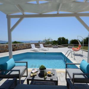 a swimming pool with chairs and a table next to a patio at Villa Selene in Alonnisos Old Town