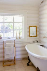 une baignoire blanche dans une salle de bains avec fenêtre dans l'établissement Beautiful And Romantic Cottage With Swimmingpool, à Melby