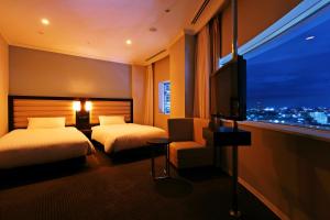 a hotel room with two beds and a flat screen tv at Palace Hotel Omiya in Saitama