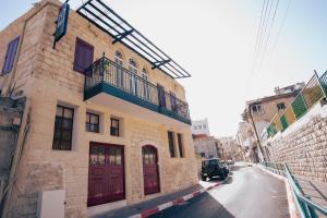 a building with red doors and a balcony on a street at Roots Boutique Hotel in Nazareth