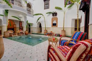 马拉喀什Riad Les Etoiles Berberes & SPA的酒店大堂设有游泳池和桌椅