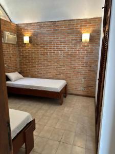 ein Zimmer mit zwei Betten und einer Ziegelwand in der Unterkunft Condominio Stoneville in São Sebastião