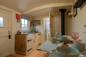 a kitchen with a table with dishes on it at ShepherdsHut-Cotswolds-PetFriendly-WoodBurner in Brackley +31 photos