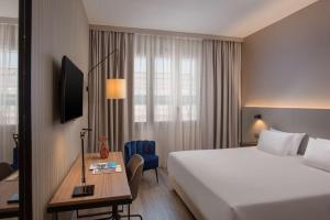 a hotel room with a bed and a desk and a bed at NH Trieste in Trieste