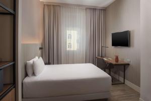 a hotel room with a bed and a television at NH Trieste in Trieste