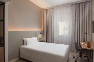 a hotel room with a white bed and a desk at NH Trieste in Trieste