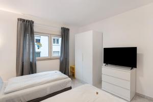 Habitación blanca con TV de pantalla plana y cama en Die Edisonstraße, en Pforzheim