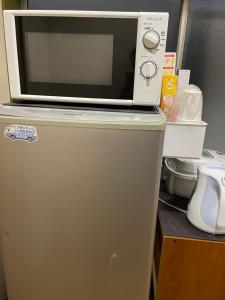東京にある平安旅馆男士迷你单身公寓の冷蔵庫の上に置かれた電子レンジ +8枚の写真