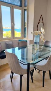 a glass table with two chairs and a vase with flowers at Turquoise view la marsa in El Haouach