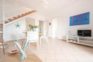 a white living room with a table and a tv at Blu Mediterraneo - IsulaTravel in Ispica