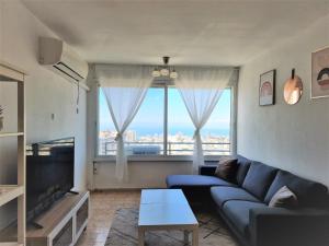 a living room with a blue couch and a large window at Sea view 2 bedroom apartment in Haifa
