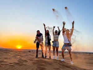 a group of people jumping in the sand on the beach at Camel Trekking Camp & Activities in Merzouga